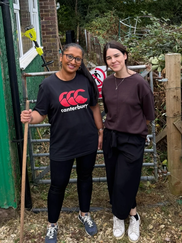 Two volunteers smiling by the gate after clearing the brambles