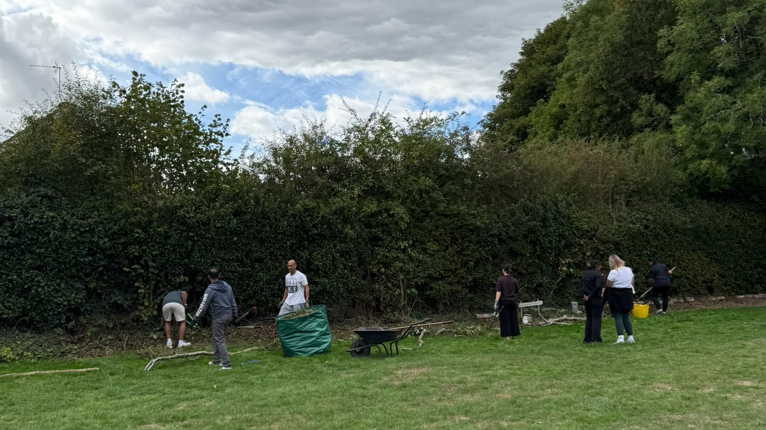 Volunteers clearing undergrowth along the hedge at the edge of the camping field